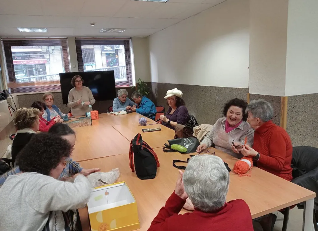 Voluntarias de Asociación ZOES Salamanca, ayudan a tejer a socias de Supo Salamanca-Avila-Zamora en el taller "Punto de encuentro"