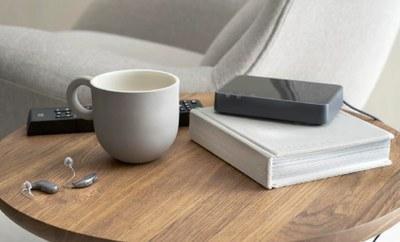 Sobre una mesa, una taza, un mando, un libro.